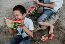 Children in uniform eating sliced watermelon
