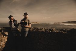 Man near woman with books near stones on shore