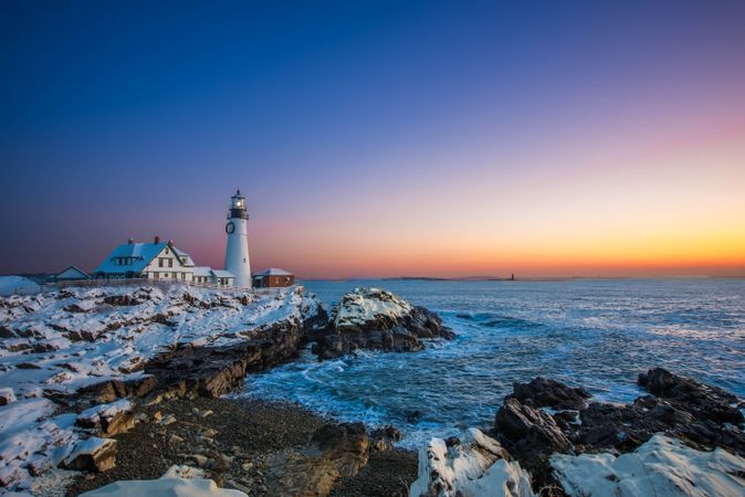 Lighthouse on rocky shore during sunset