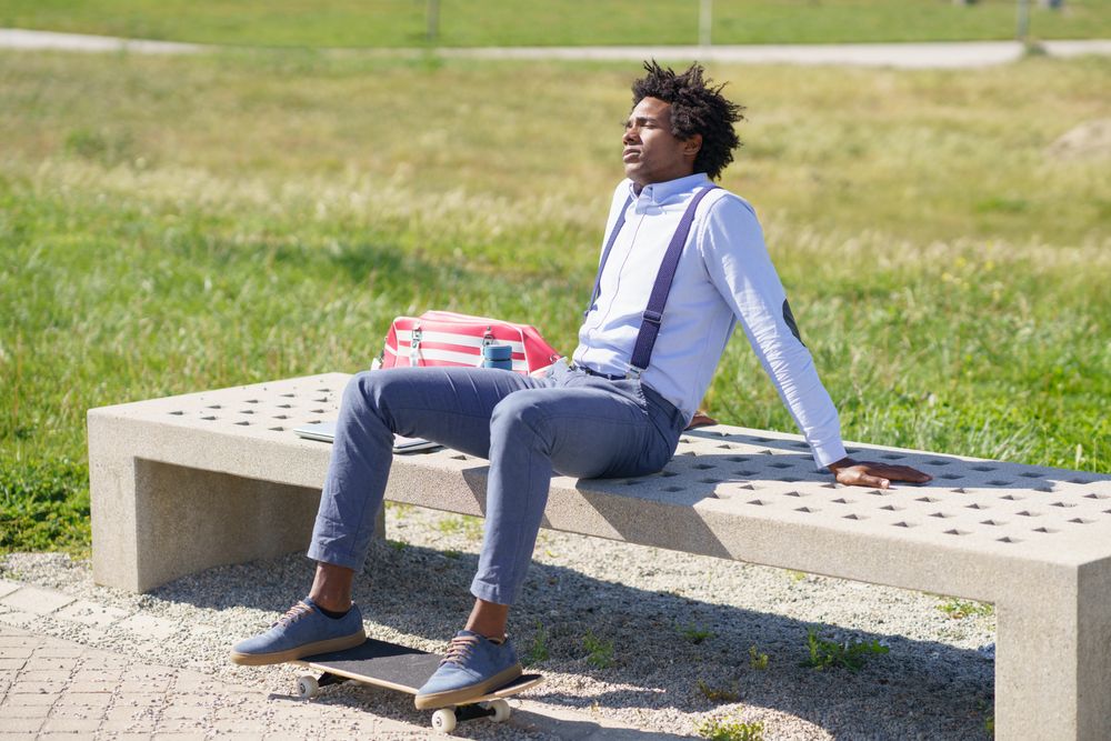 Man relaxing on concrete bench with skateboard