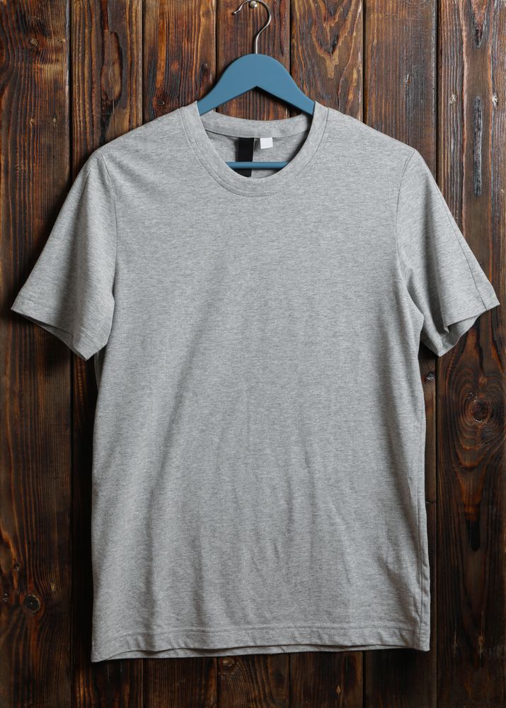 Hanger with blank gray t-shirt on wooden background, space for text