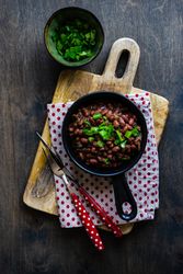 Top view of traditional Georgian lobio dish with green onions on wooden table with dotted kitchen towel