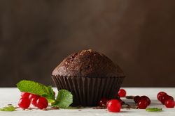 Chocolate muffin and berries against brown background