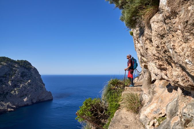 Male hiker admiring picturesque blue sea in mountains