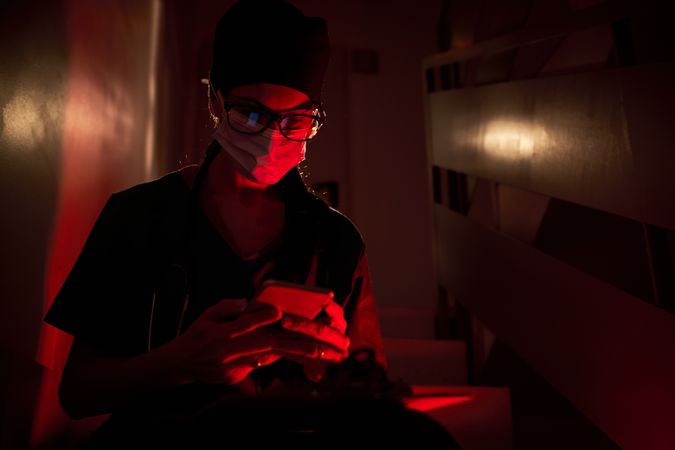 Serious medic browsing cellphone on staircase