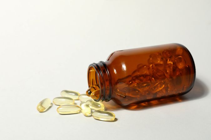 Brown bottle with omega pills on plain background
