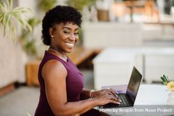 Woman in purple top working on her laptop 4jMwv5