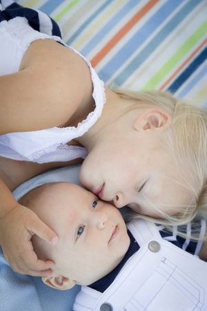 Little Sister Laying Next to Her Baby Brother on Blanket