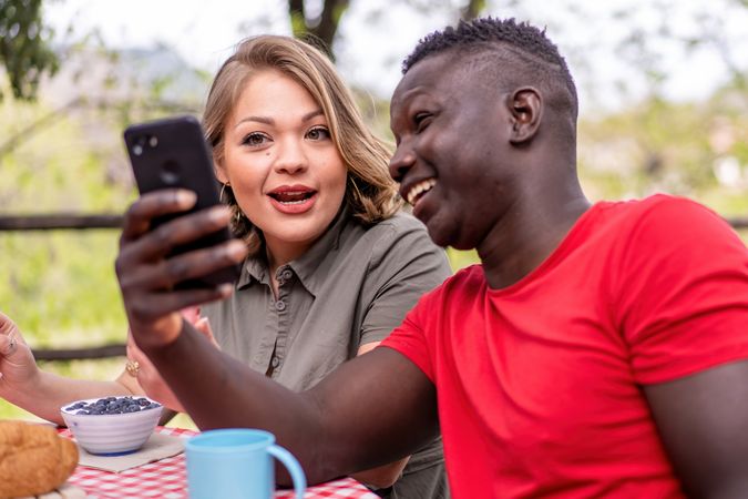 A multi-ethnic couple shares a funny moment over a smartphone