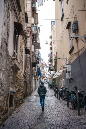 Anonymous female traveler in warm wear walking on narrow old street