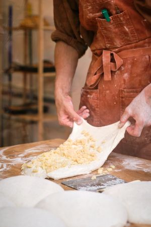 Detail of a baker's hands introducing ingredients into the bread