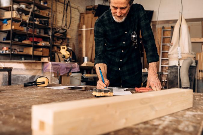 Older man drawing plans in his woodwork shop