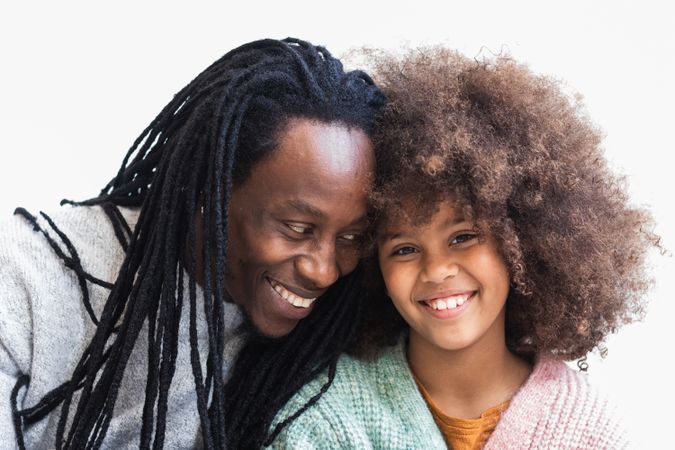 Delighted Black man cuddling with daughter