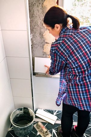 Female bricklayer laying tile on the wall