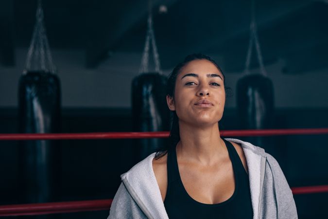 Confident female boxer standing in the ring in hoodie