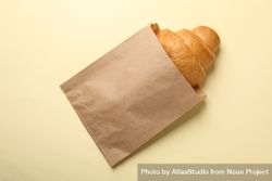 Craft paper bag with croissant on beige background, copy space 5Xx1G5