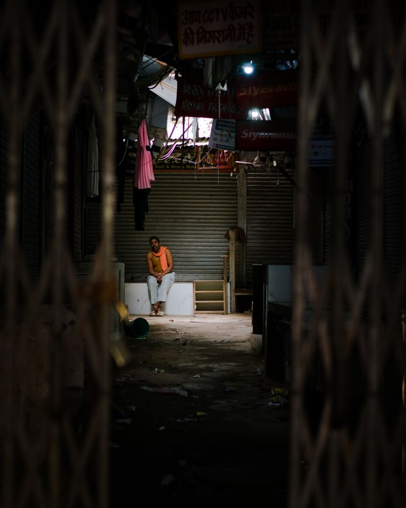 Topless man sitting on bench in an alley