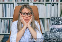 Overwhelmed woman next to box of documents in office 5ngWY2