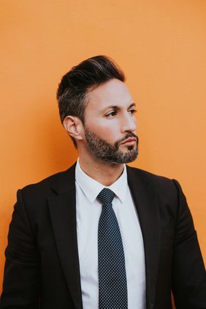 Adult stylish man in costume near orange wall