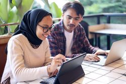 Asian Hijab Female Working at the Cafe with Her Colleague