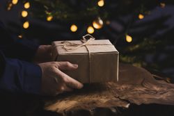 Man holding Christmas gift by wooden table