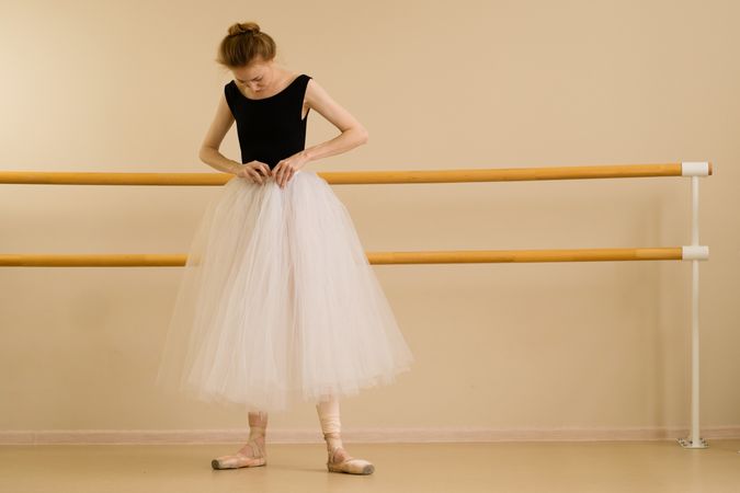 Ballet dancer adjusts her tutu in dance studio