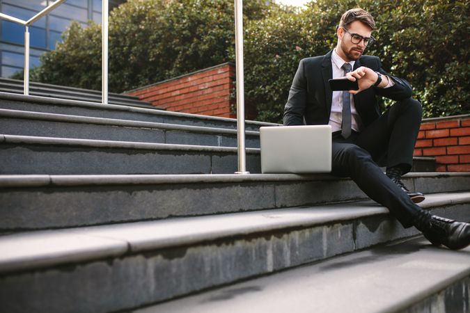 Business professional waiting for someone outdoors sitting on stairs