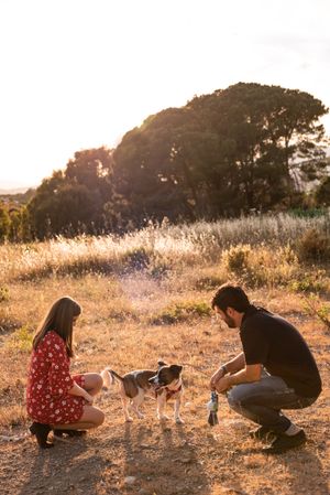 Happy couple with friendly cute dog resting outdoors