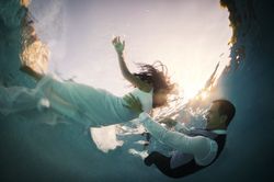 Bride and groom swimming underwater