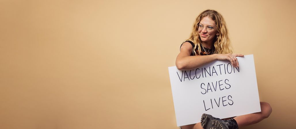 Woman holding a banner with ”vaccination saves lives" slogan
