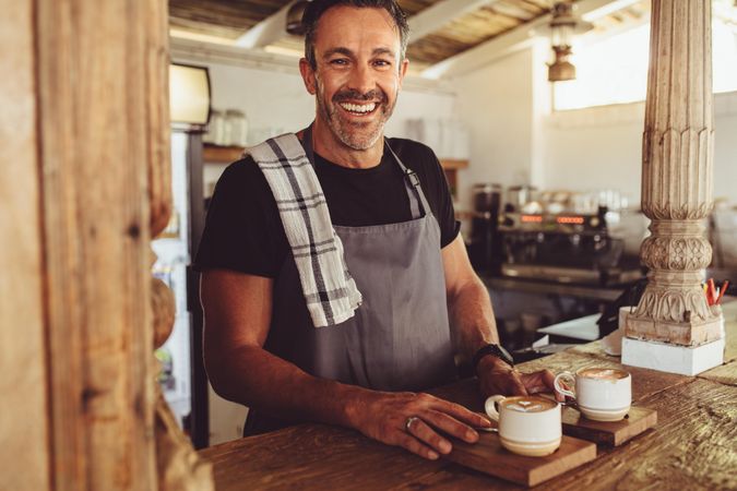 Cheerful male barista serving coffee to customers