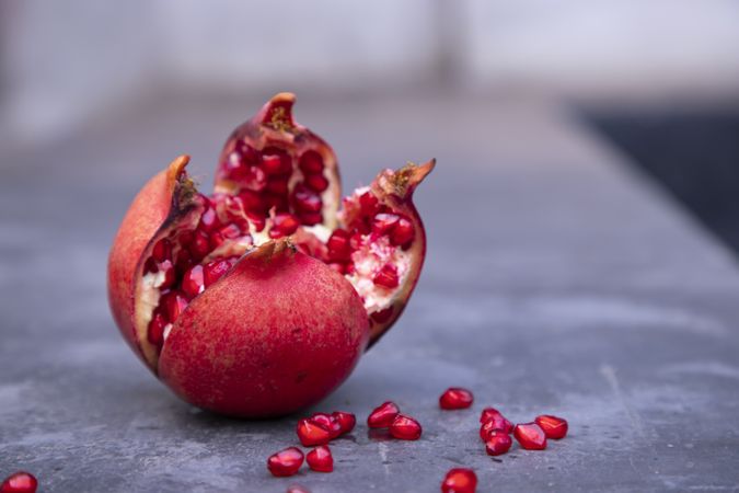 Ripe pomegranate fruit with seeds on a gray background