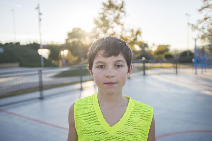 Portrait of a teenage male wearing a yellow basketball sleeveless shirt on court