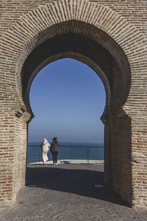 Arch of building and women looking at seascape