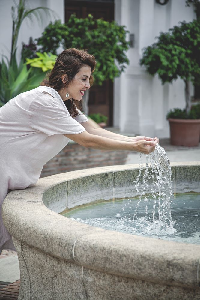 Joyful female splashing water in city fountain