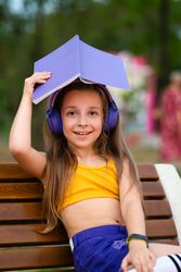 Preteen school girl with book on bench in park