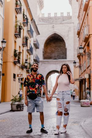 trendy couple holding hands on street
