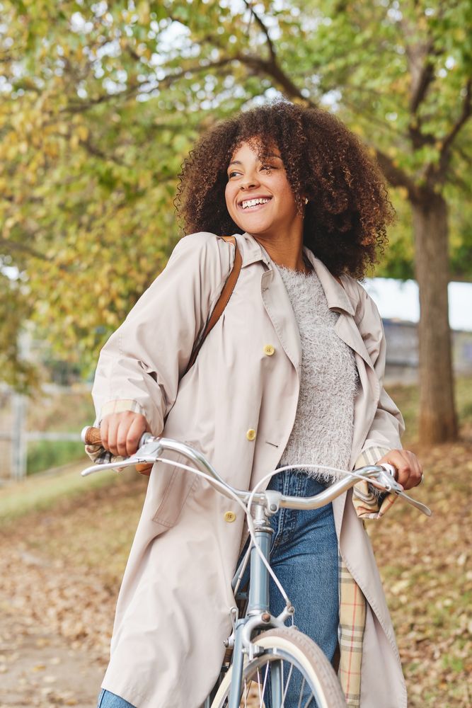 Smiling Black woman with bicycle in park