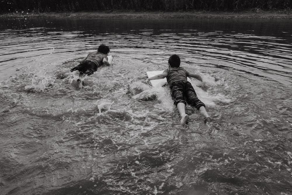 Happy boys swimming with board over water