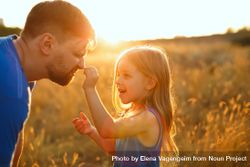 Happy man and daughter  dressed in blue playing in sunny field 4Zzq34