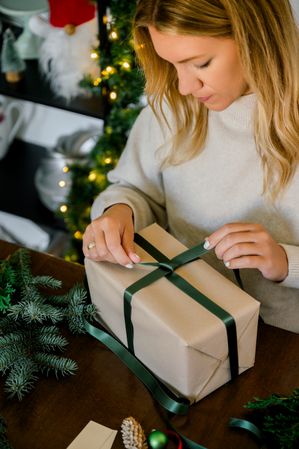 woman wrapping christmas gift at home