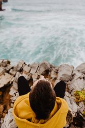 Person in yellow hoodie on stony shore