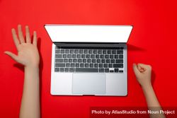 Top view of person’s hands next to laptop keyboard on red table 0vJwG0