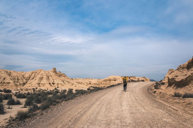 Man walking on road in desert hills