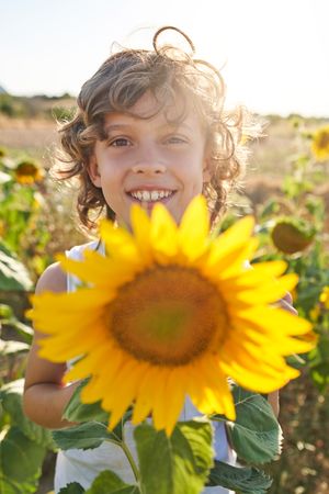 Positive boy with sunflower in countryside