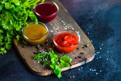 Yraditional Georgian condiments tomato satsebeli, yellow and red tkemali on wooden board