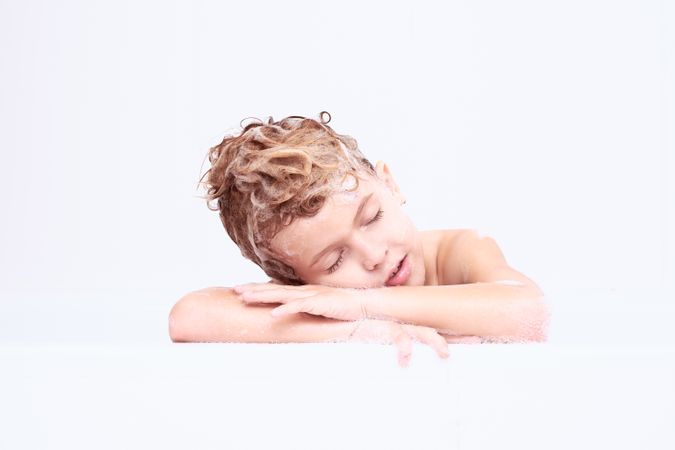 Boy with soapy head sleeping in bathroom