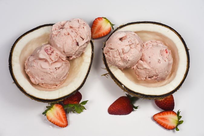 Top view of two coconut shells with ice cream and strawberry fruit pieces