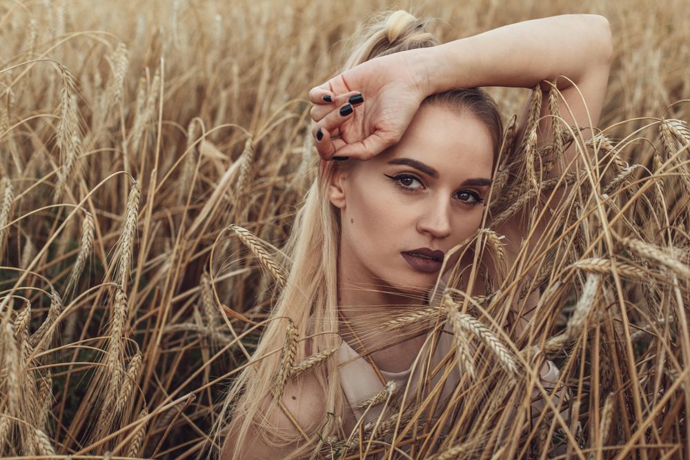 Portrait of young woman with purple lipsticks in wheat field