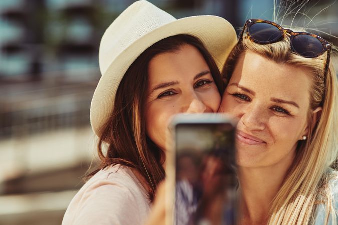 Women smiling and taking selfie on sunny day, close up